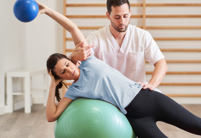 Physiotherapeut in der Übung mit dem Patienten an einem Gymnastikball